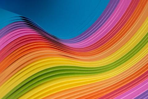 Buntes Papier in Regenbogenfarben übereinander gelegt und wellenförmig zusammen geschoben