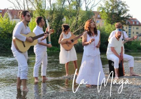 Die Band La Maga musiziert mit Gitarren und Cajon in einem Fluss